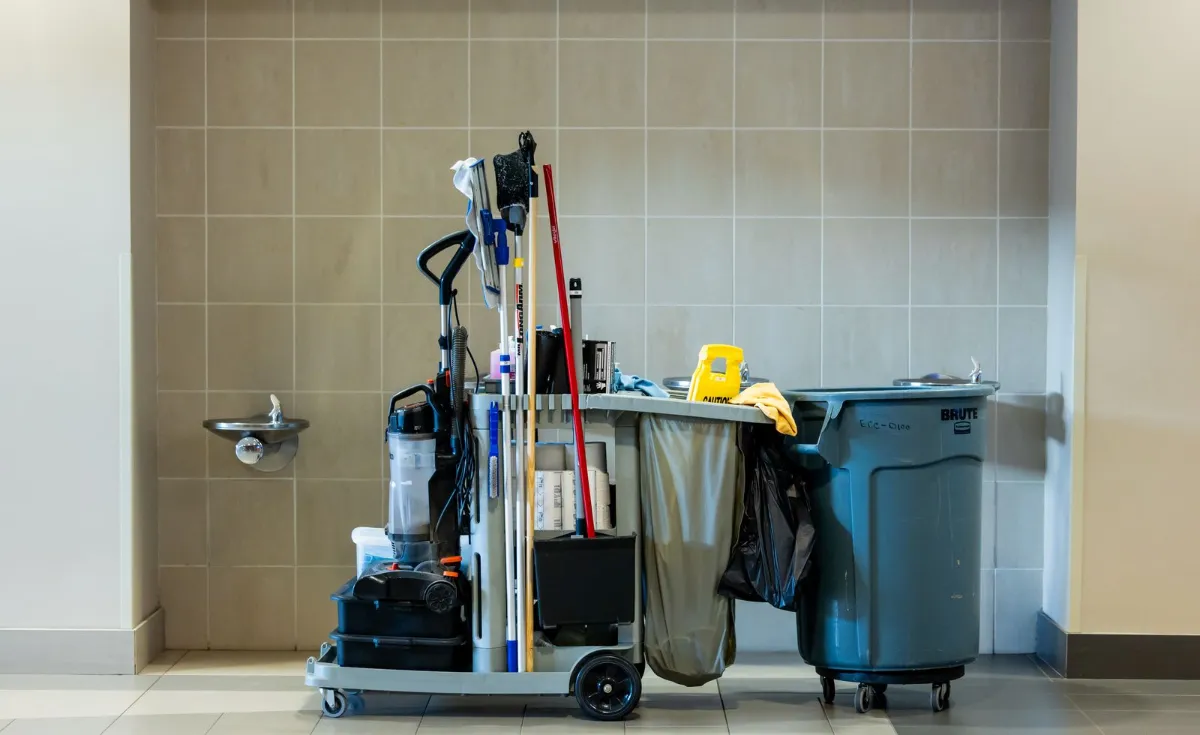 Cleaning cart with mops, supplies, and waste bins in a tiled clinic room during medical office cleaning in Rogers, AR