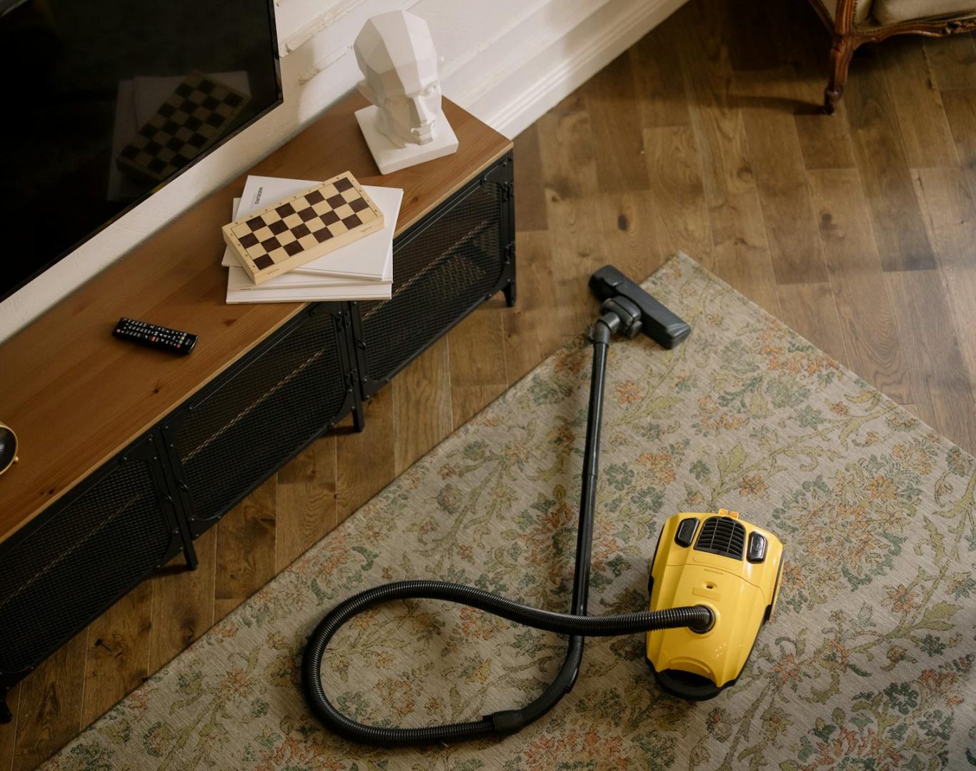 Warm living room scene featuring a yellow vacuum on a floral carpet with a vintage vibe.