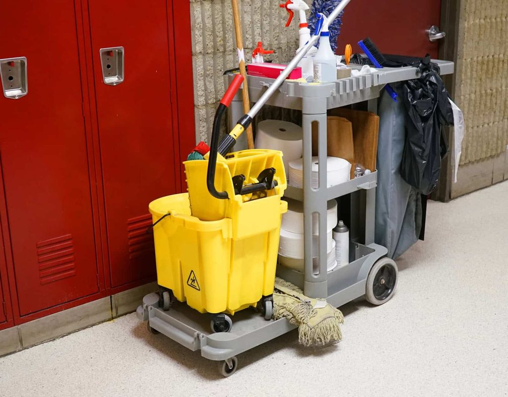 Day porter disinfecting high touch surfaces inside office building during business hours
