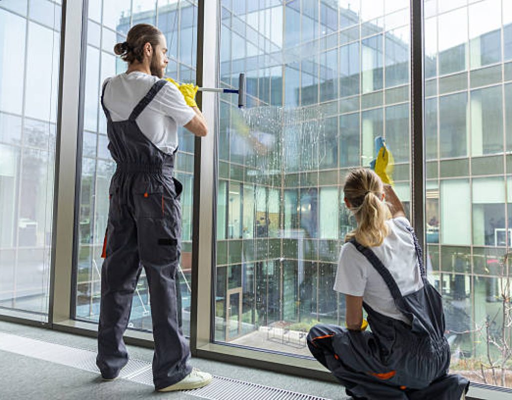 Technician cleaning exterior windows of a Fayetteville, AR office building after a spring storm