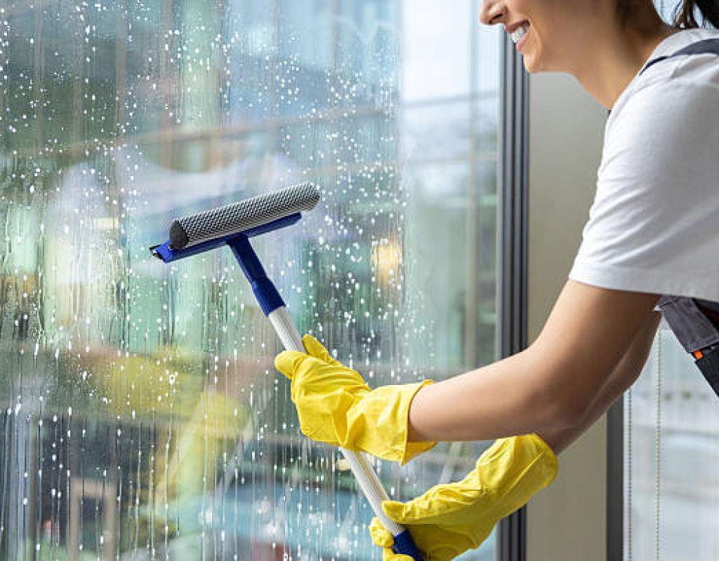 Uniformed technician cleaning large storefront windows in downtown Centerton, AR